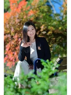 Avery Quan 坐在公园长椅上,周围是秋叶